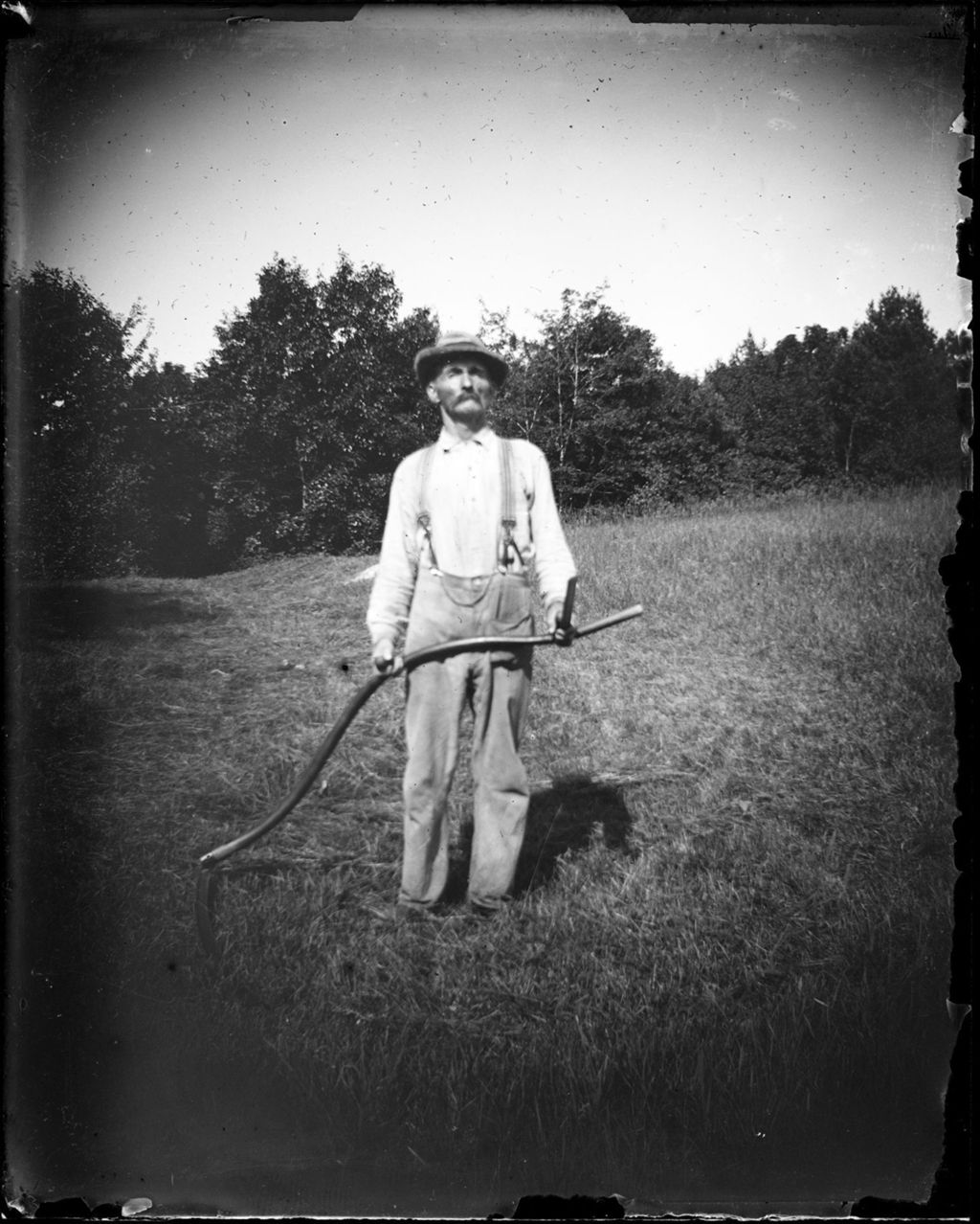 Miniature of Old Man Standing In A Hay Field Holding A Scythe