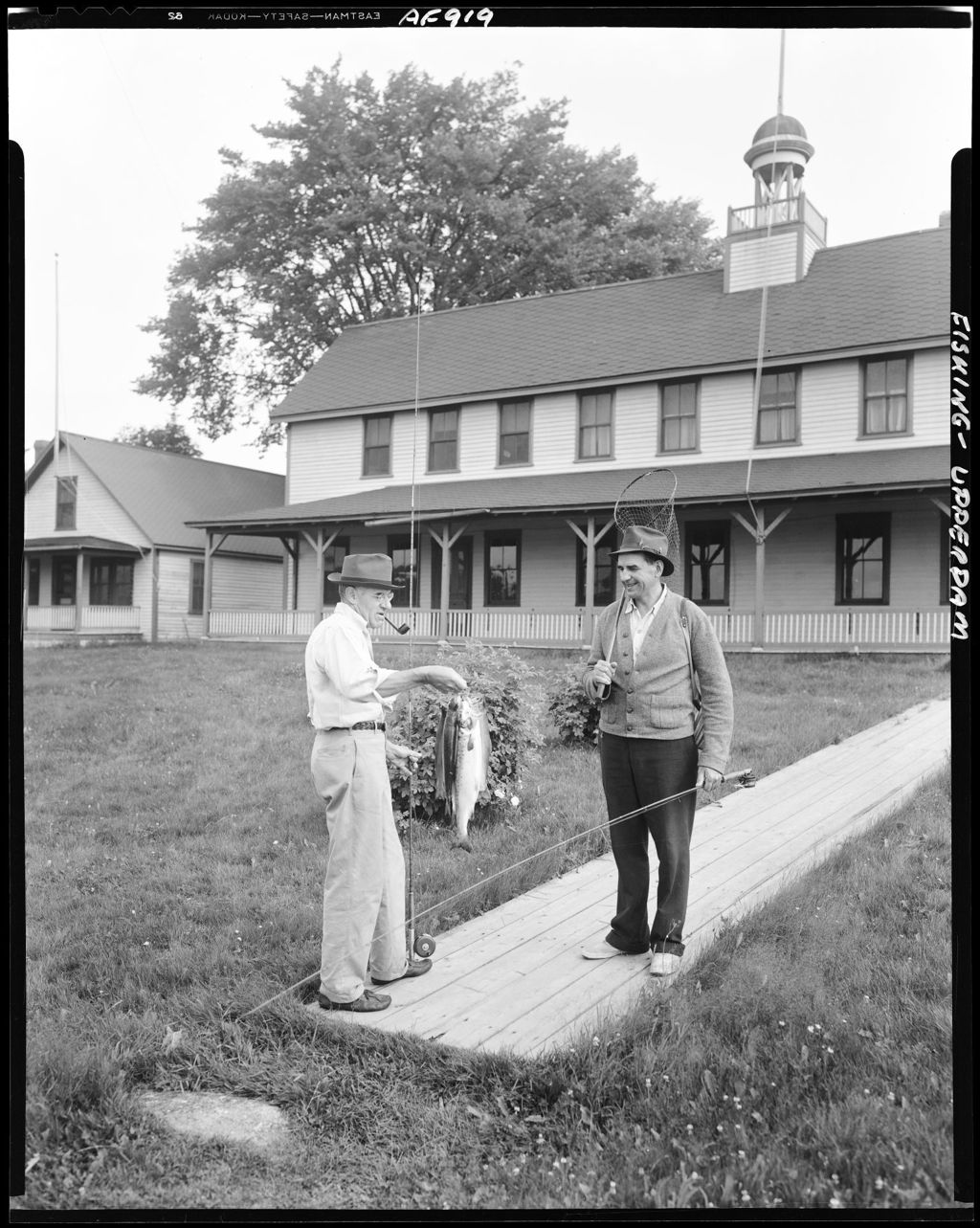 Miniature of Two Men On Walkway At Camp At Upper Dam, One Showing Fish To The Other