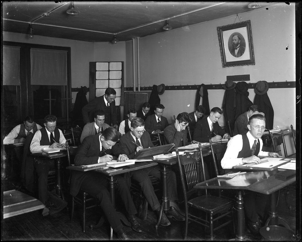 Miniature of Male College Students In Classroom Studying While Teacher Looks On