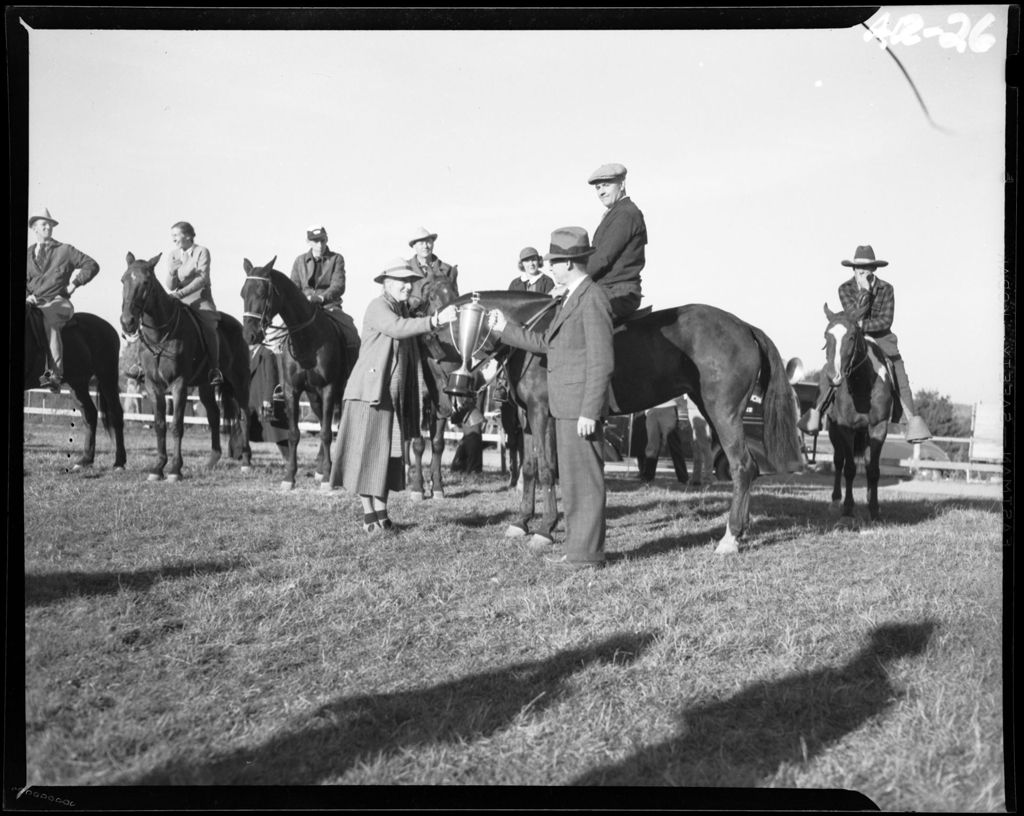 Miniature of Man And Woman Holding Trophy, Group Of Riders In Background