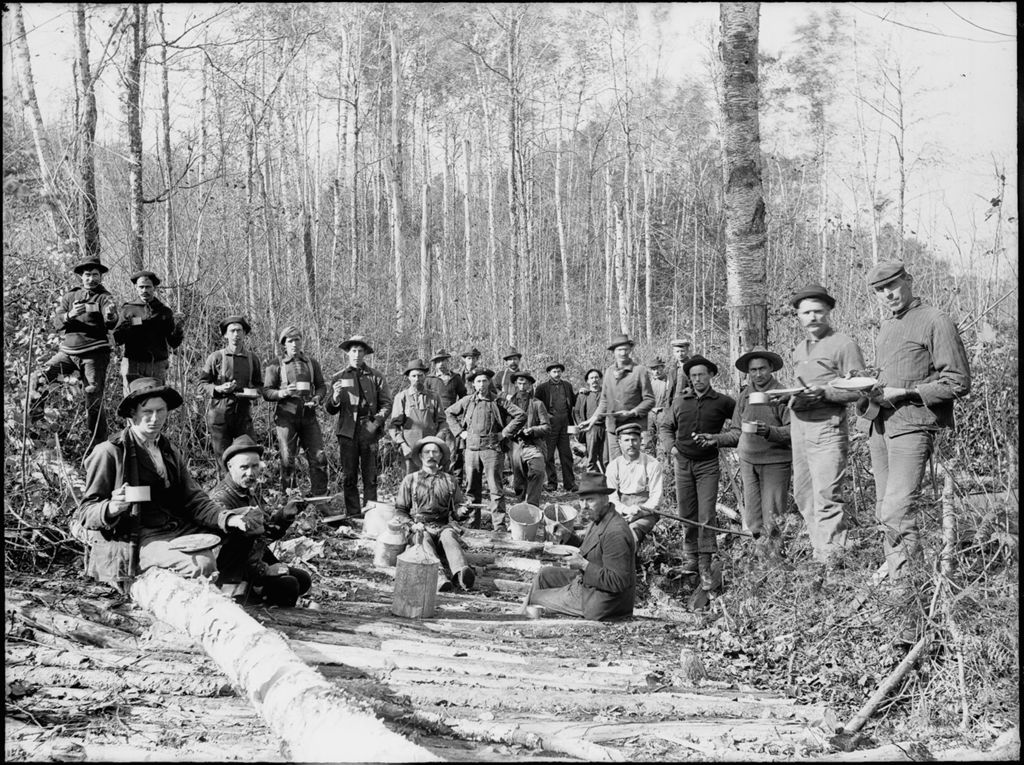 Miniature of Woodland scene of many men from a logging camp eating an afternoon meal