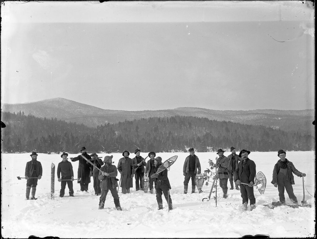 Miniature of Men from a logging camp outside on a snow covered frozen lake with hills in the distance