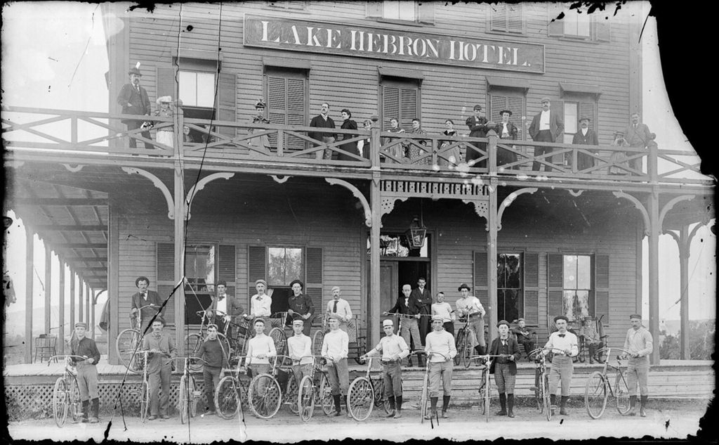 Miniature of Group of men with bicycles out side the Lake Hebron Hotel, many people standing on the second floor veranda